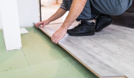 Young worker laying a floor with bright laminated flooring boards